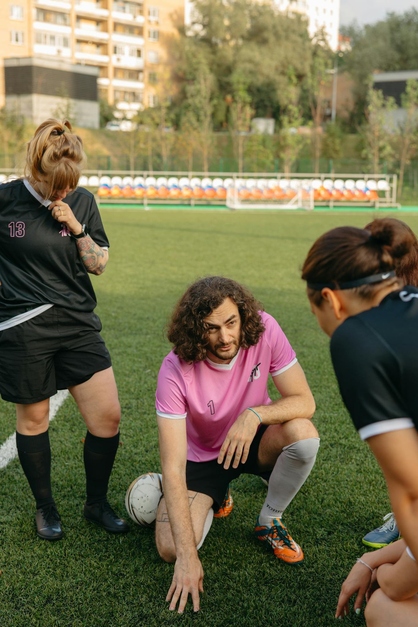 Soccer coach instructs players on strategy during outdoor training session on grass field.